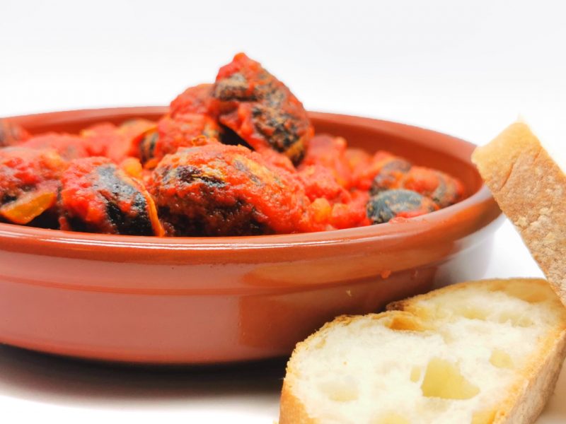 Plato de caracoles con tomate, chorizo y jamón.
